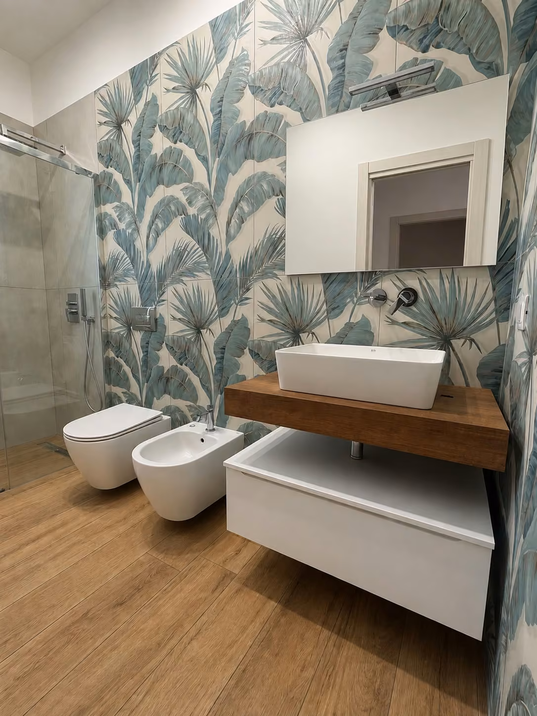 Bagno con rivestimento tropicale, mobile sospeso e lavabo bianco