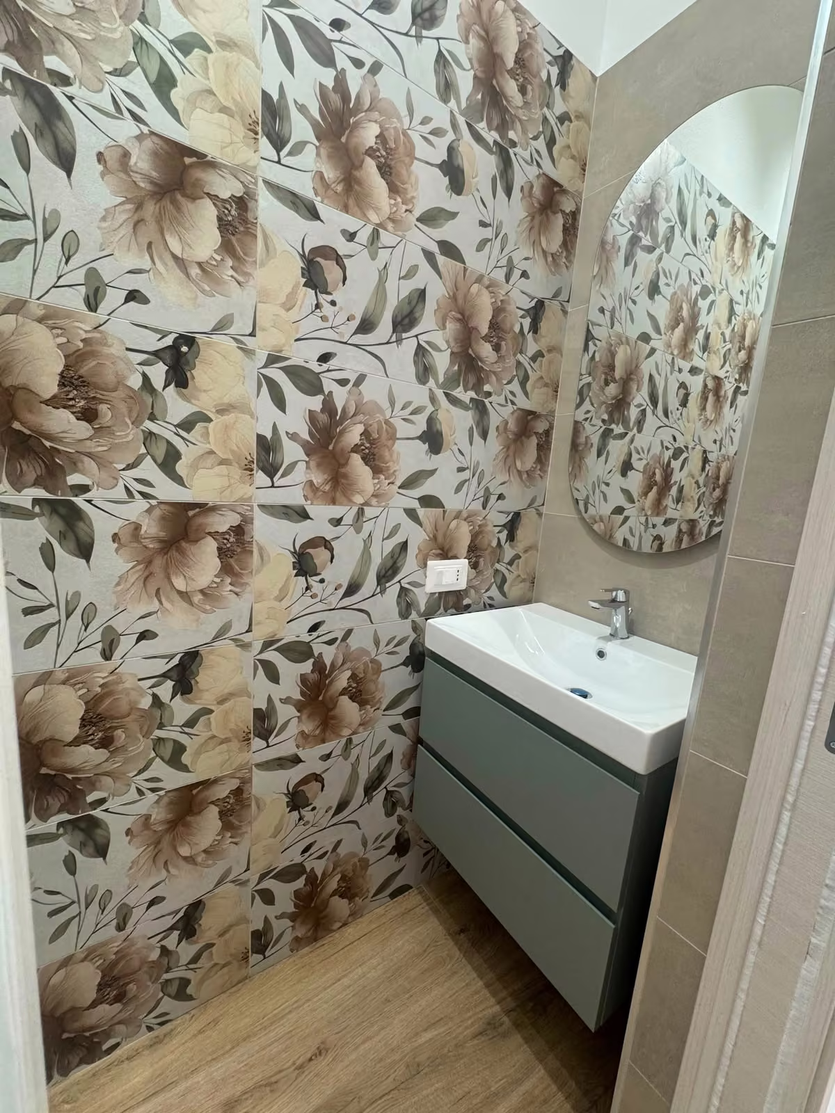Bagno con rivestimento floreale e mobile verde