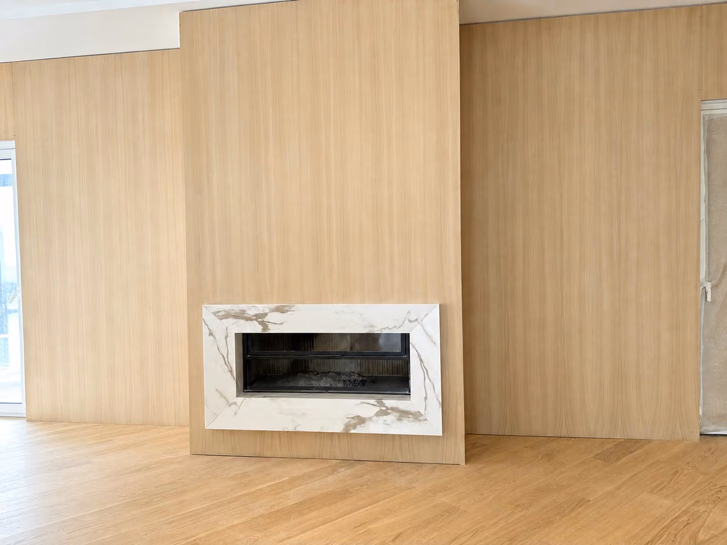 Cornice del camino in materiale bianco venato su una parete effetto legno