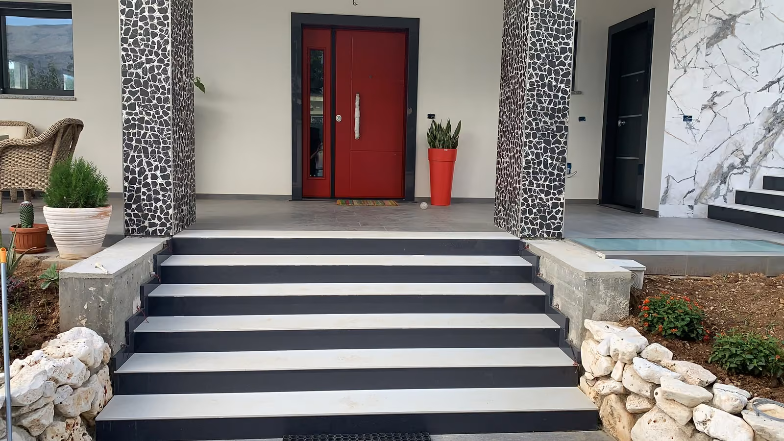Scala esterna con gradini chiari e alzate scure davanti a un ingresso